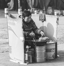 大妈煎油饼用纸箱挡寒风走红感叹不容易