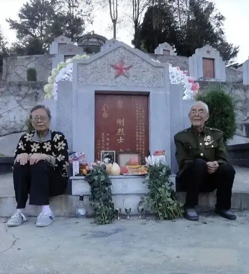 两位老人从千里之外赶到儿子墓地,在墓碑前照下了一张全家福