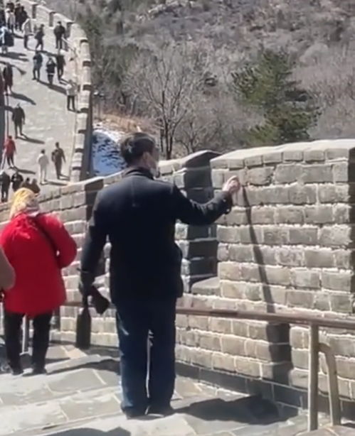 八达岭长城,两名大妈和一名大爷轮流在城墙上用利器刻自己的名字