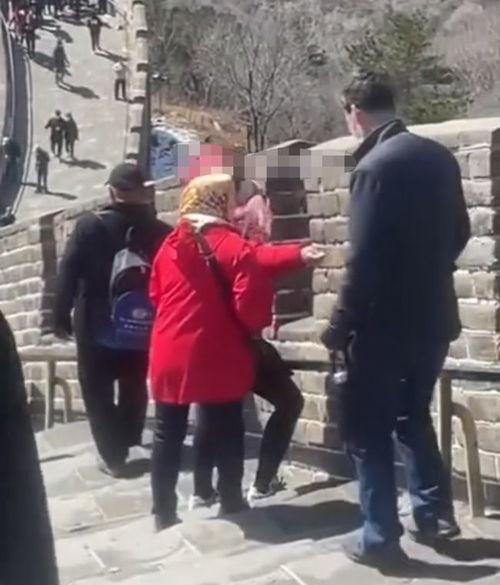 八达岭长城,两名大妈和一名大爷轮流在城墙上用利器刻自己的名字